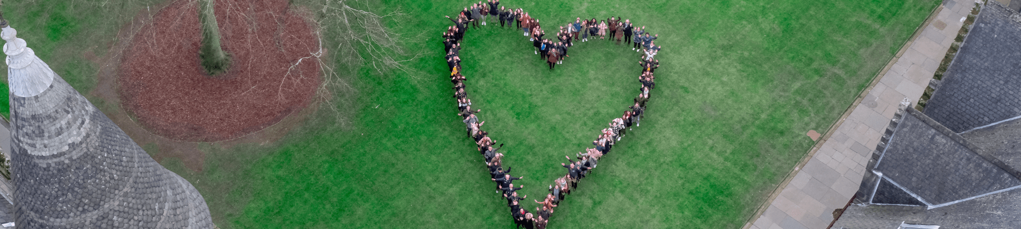 Aerial image of staff in a heart shape, standing outside at the Gilbert Scott Building